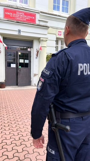 Policjant przed wejściem do szkoły.