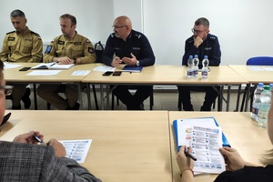 Przy stole siedzą dwaj policjanci i dwaj strażacy.