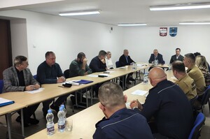 W pomieszczeniu są dwa długie stoły, przy których siedzą uczestnicy spotkania. W szczycie siedzi starosta i jego zastępca.